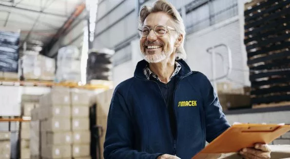 Mann mit Klemmbrett steht in Lagerhalle