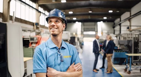 Mann mit blauem Helm steht in Lagerhalle