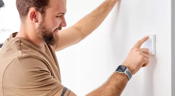 Mann steht an digitalem Steuerungsmodul in einem Haus