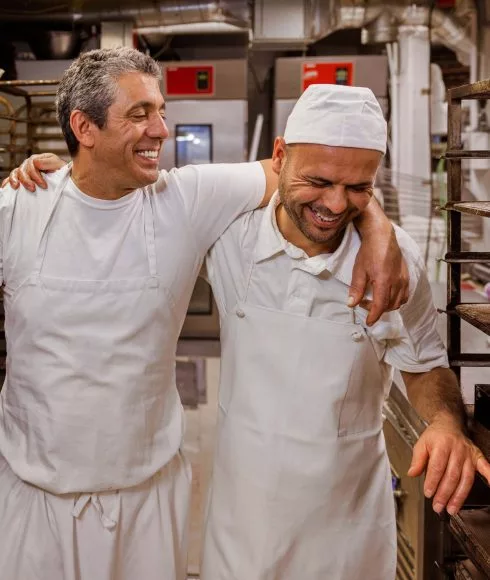 Zwei Bäcker halten sich in den Armen und lachen