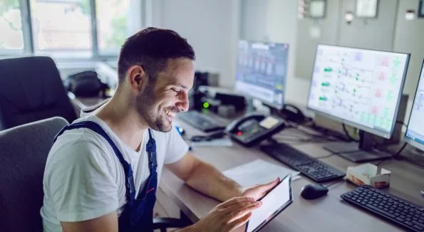 Mann im blauen Overall arbeitet an Tablet und Computer