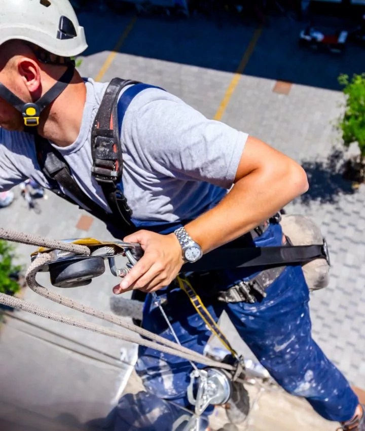 Mann reinigt Außenwand von Gebäude