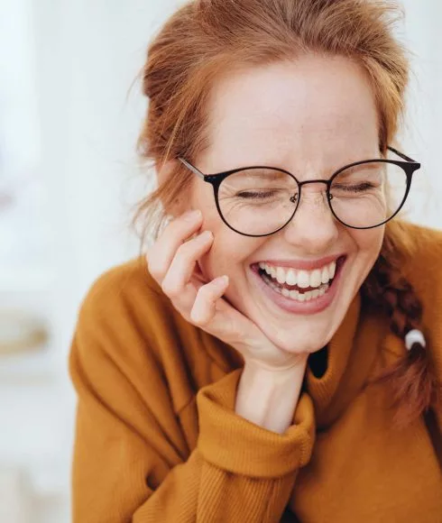 Frau mit braunem Pulli und roten Haaren lacht