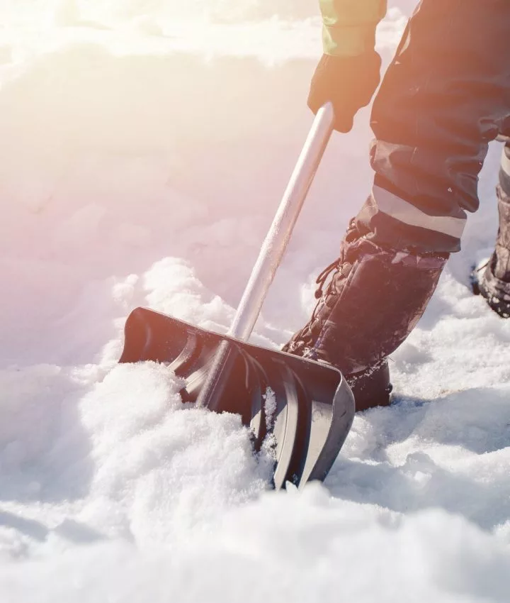 Person räumt Schnee mit Schneeschaufel
